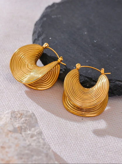 Gold spiral earrings on neutral background