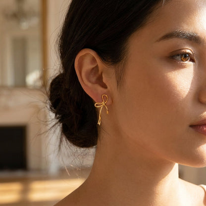 Bow-shaped gold drop earrings – close-up detail
