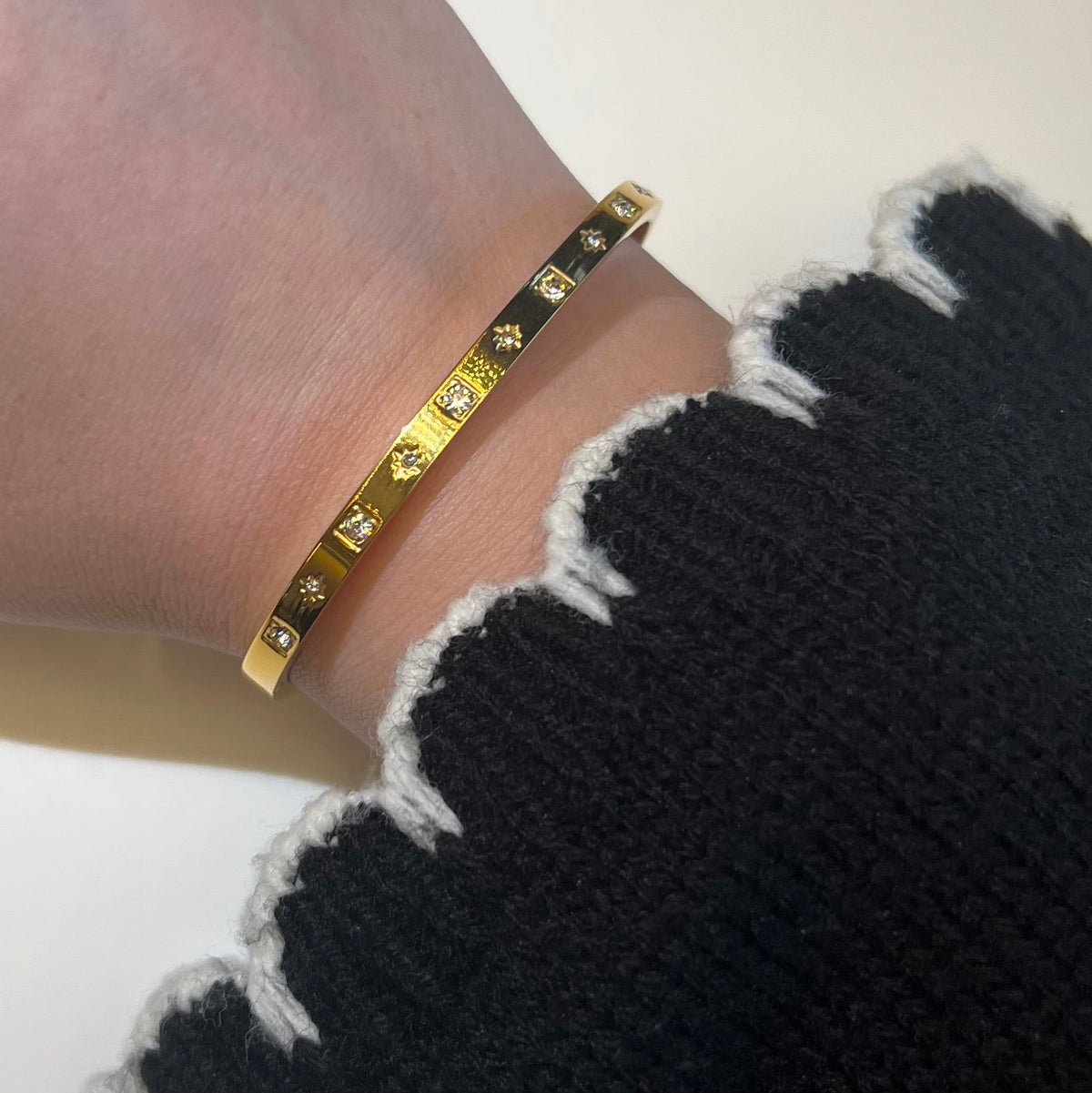 Gold bangle with star-set stones on neutral background