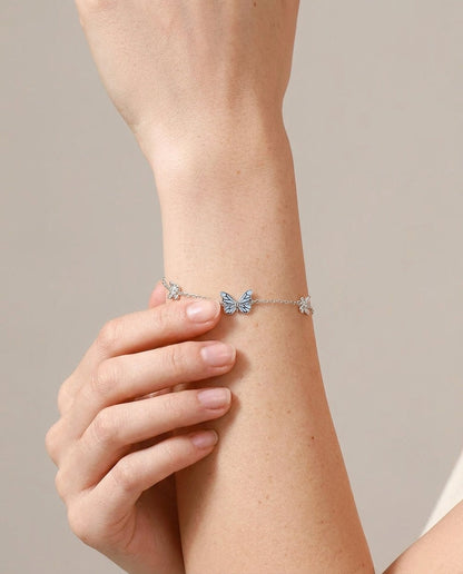 Glow-in-the-dark butterfly bracelet on wrist, hand-set enamel charm