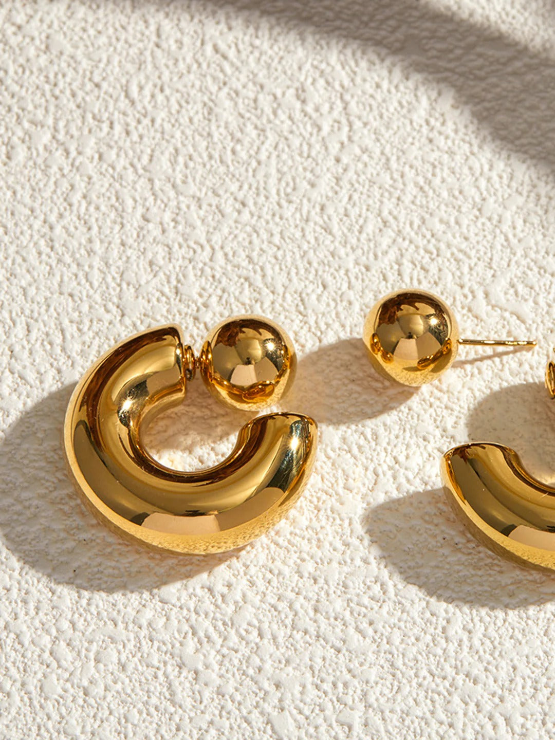 Chunky C-shaped hoop earrings styled on a model's ear