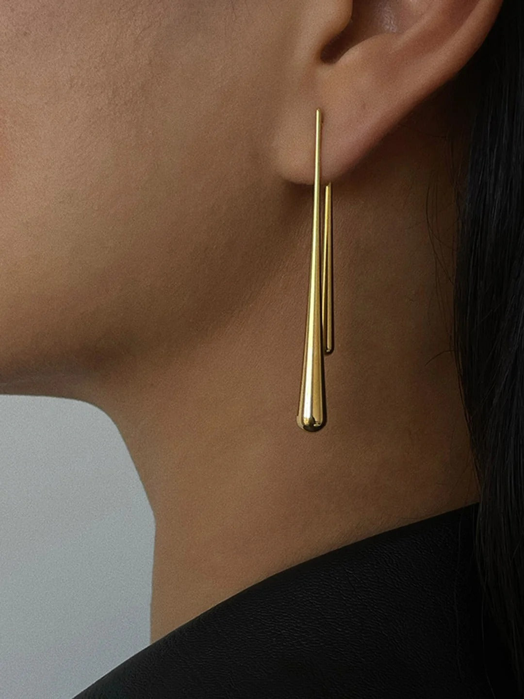 Asymmetrical water drop earrings on neutral background
