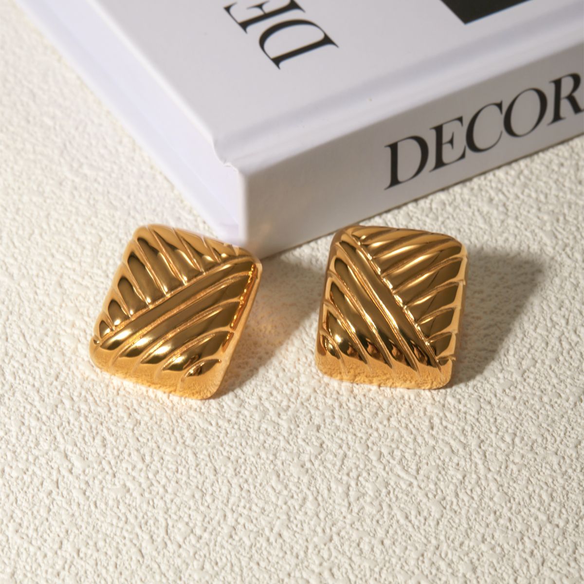 Gioiello gold earrings on neutral background