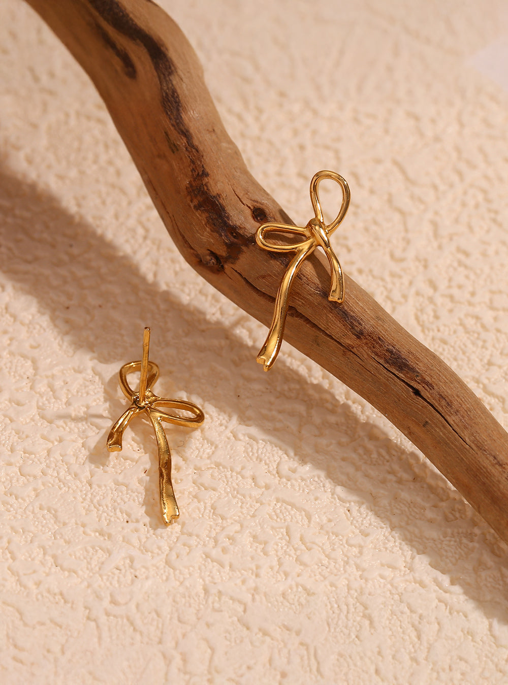 Delicate gold bow earrings – texture detail