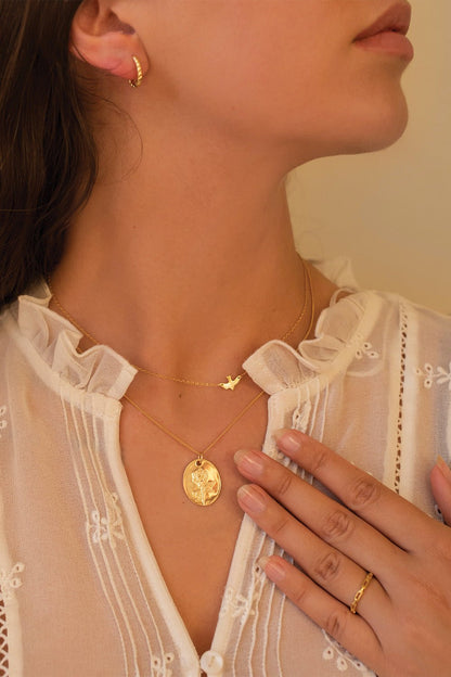 Close-up of delicate gold bird pendant on fine chain