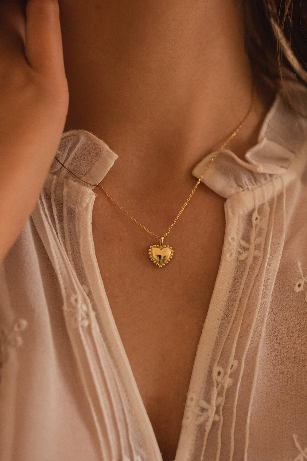 Gold heart love necklace styled on a model's neckline