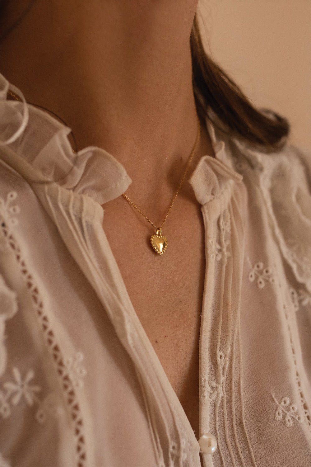 Close-up of ribbed gold heart pendant on fine chain