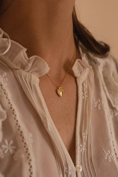 Close-up of ribbed gold heart pendant on fine chain