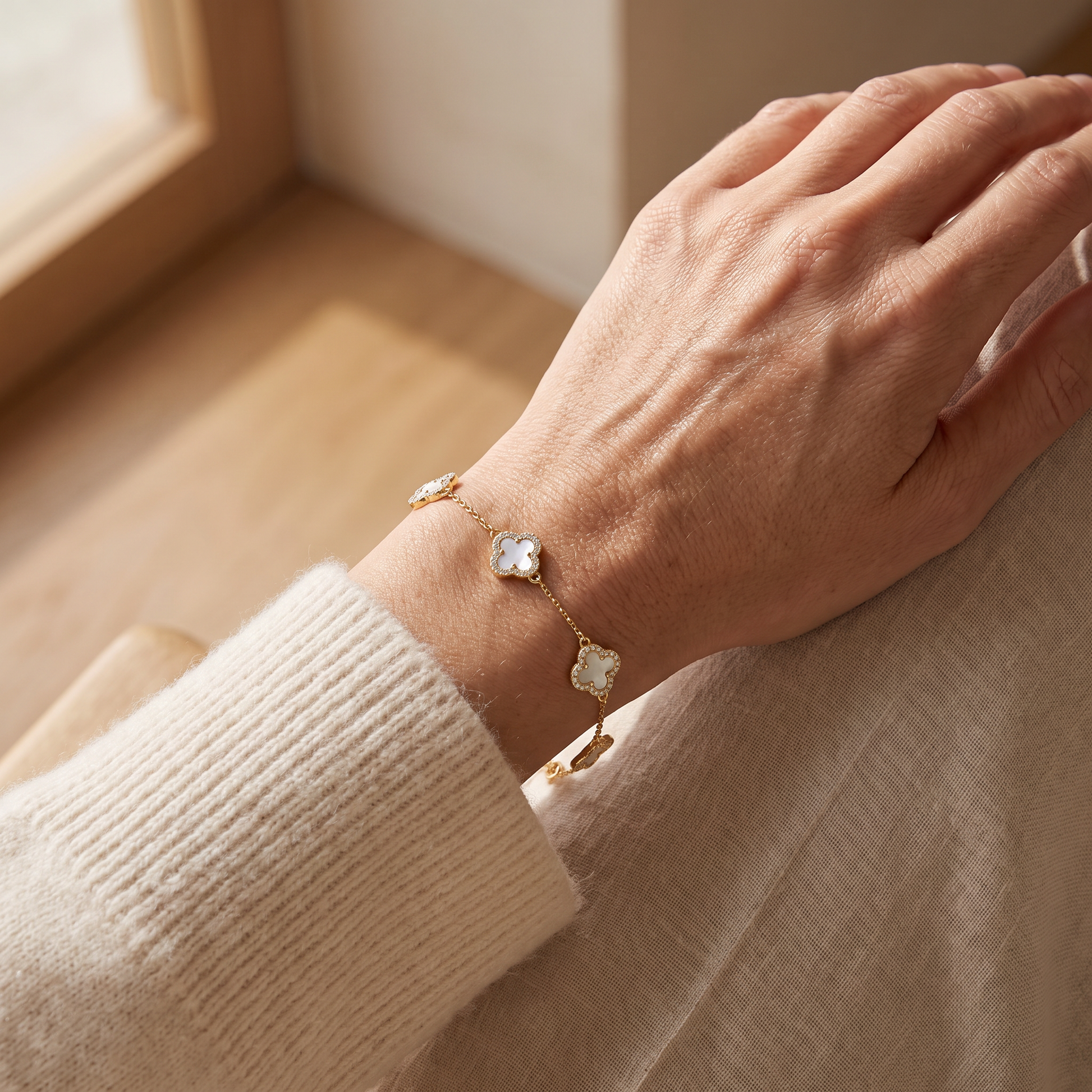 Ravyena clover mother-of-pearl bracelet worn on a woman's wrist in natural daylight
