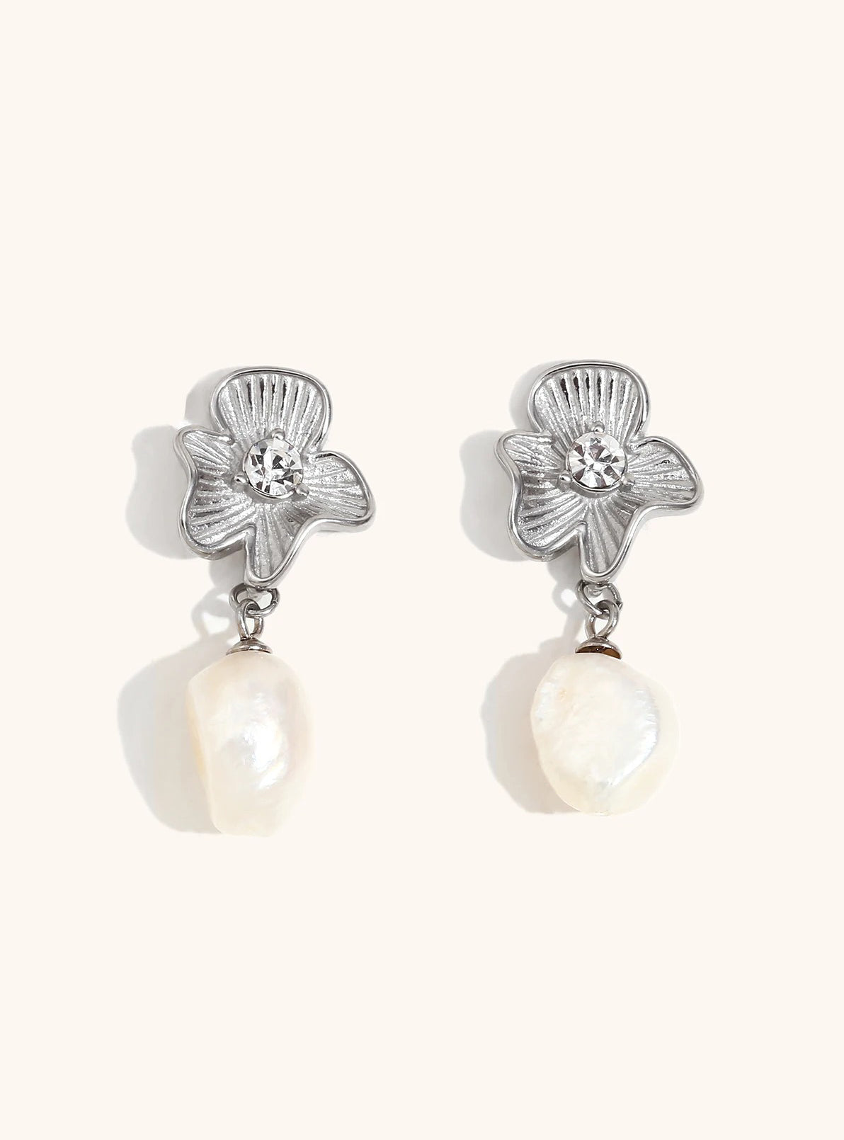 Gold floral earrings on neutral background