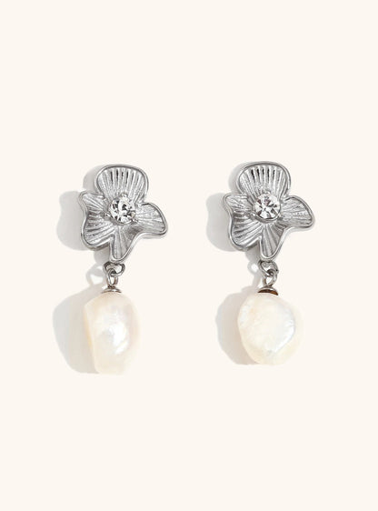 Gold floral earrings on neutral background