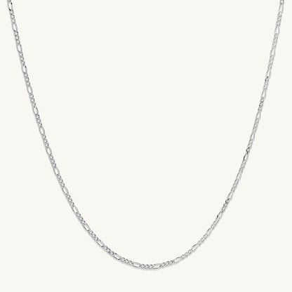 Gold figaro chain on neutral background