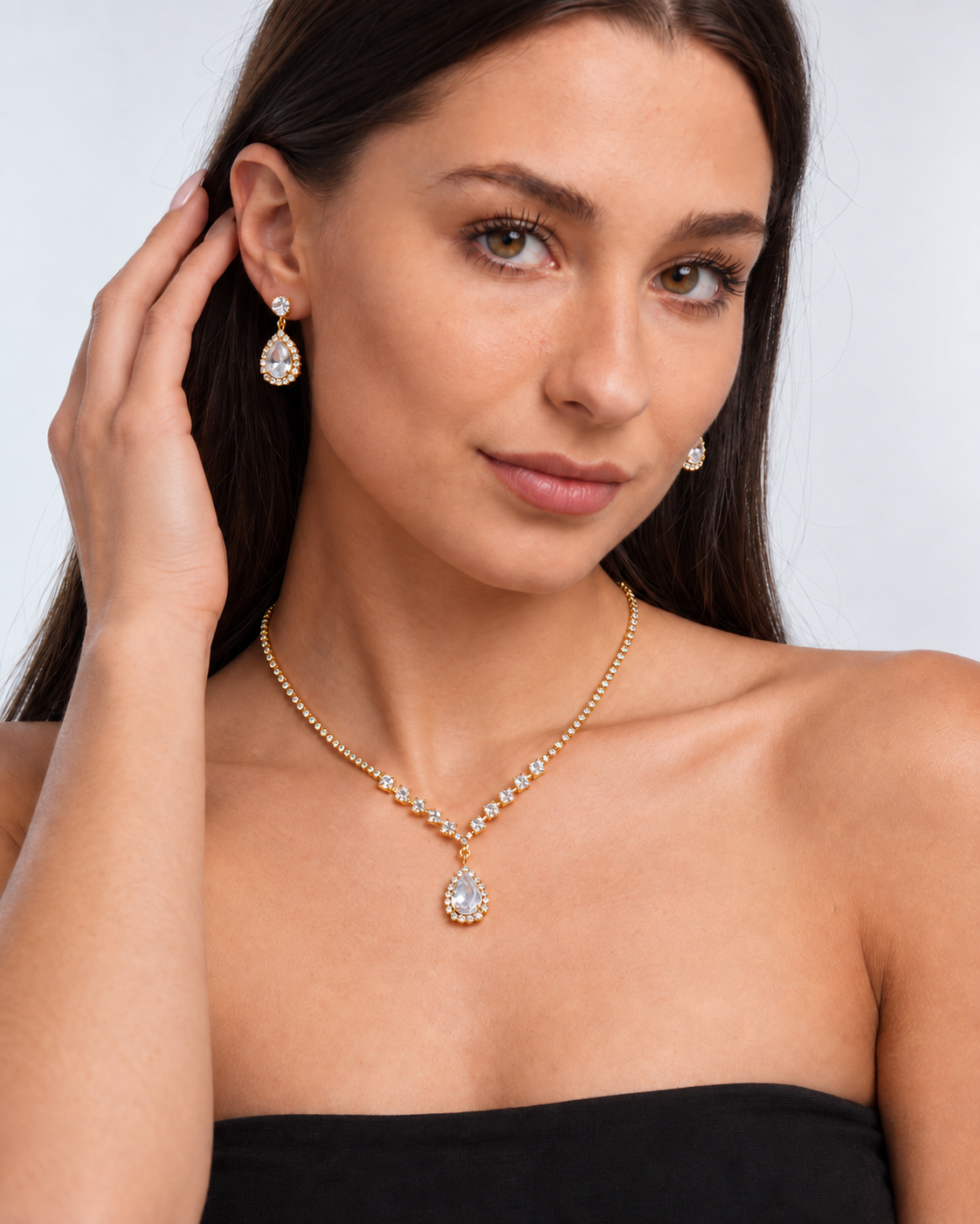 Crystal Teardrop Necklace & Earring Set in Gold / Clear, worn by a model in a three-quarter portrait - Vessaly