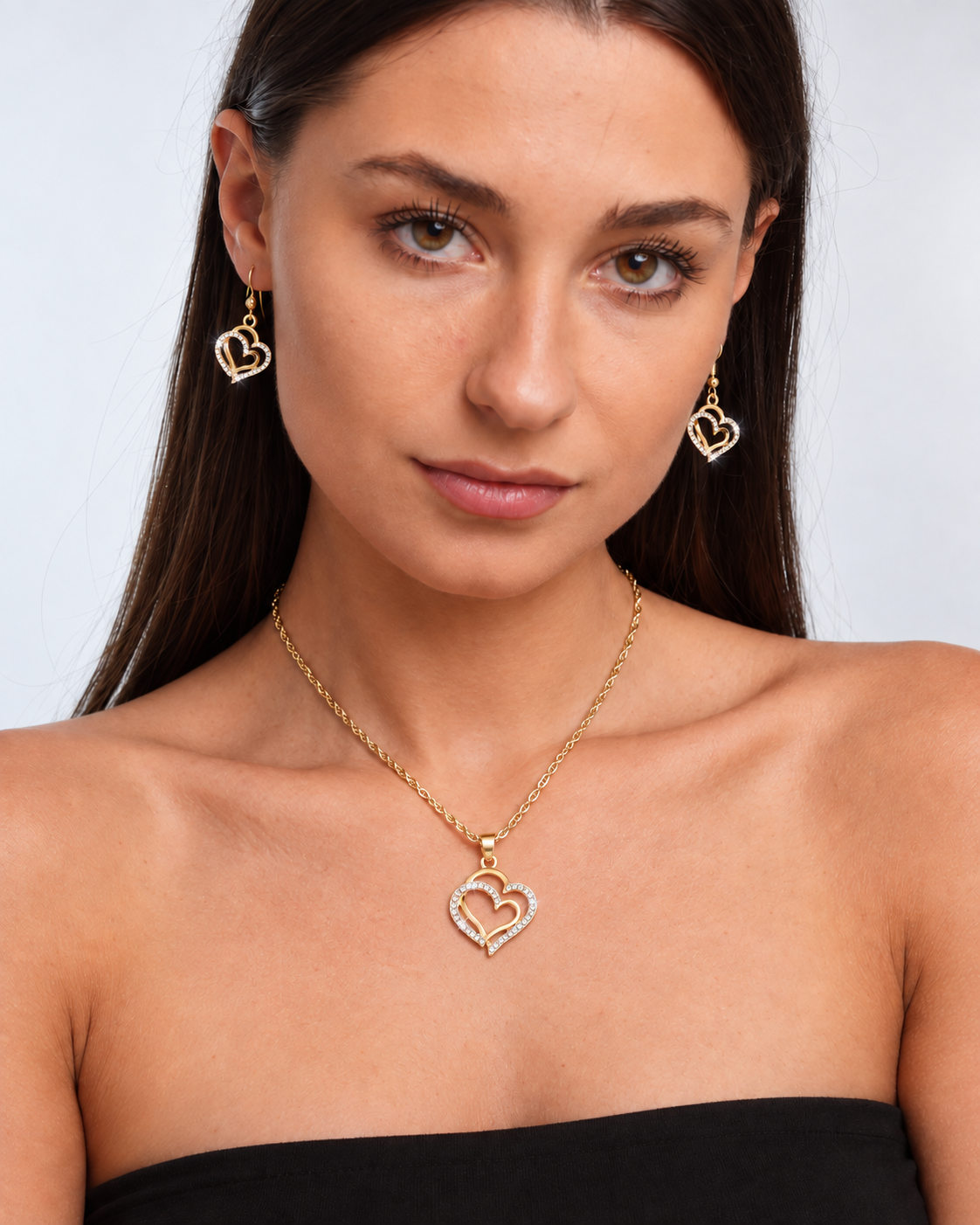 Double Heart Crystal Necklace & Earring Set in Gold, worn by a model in a front portrait - Vessaly
