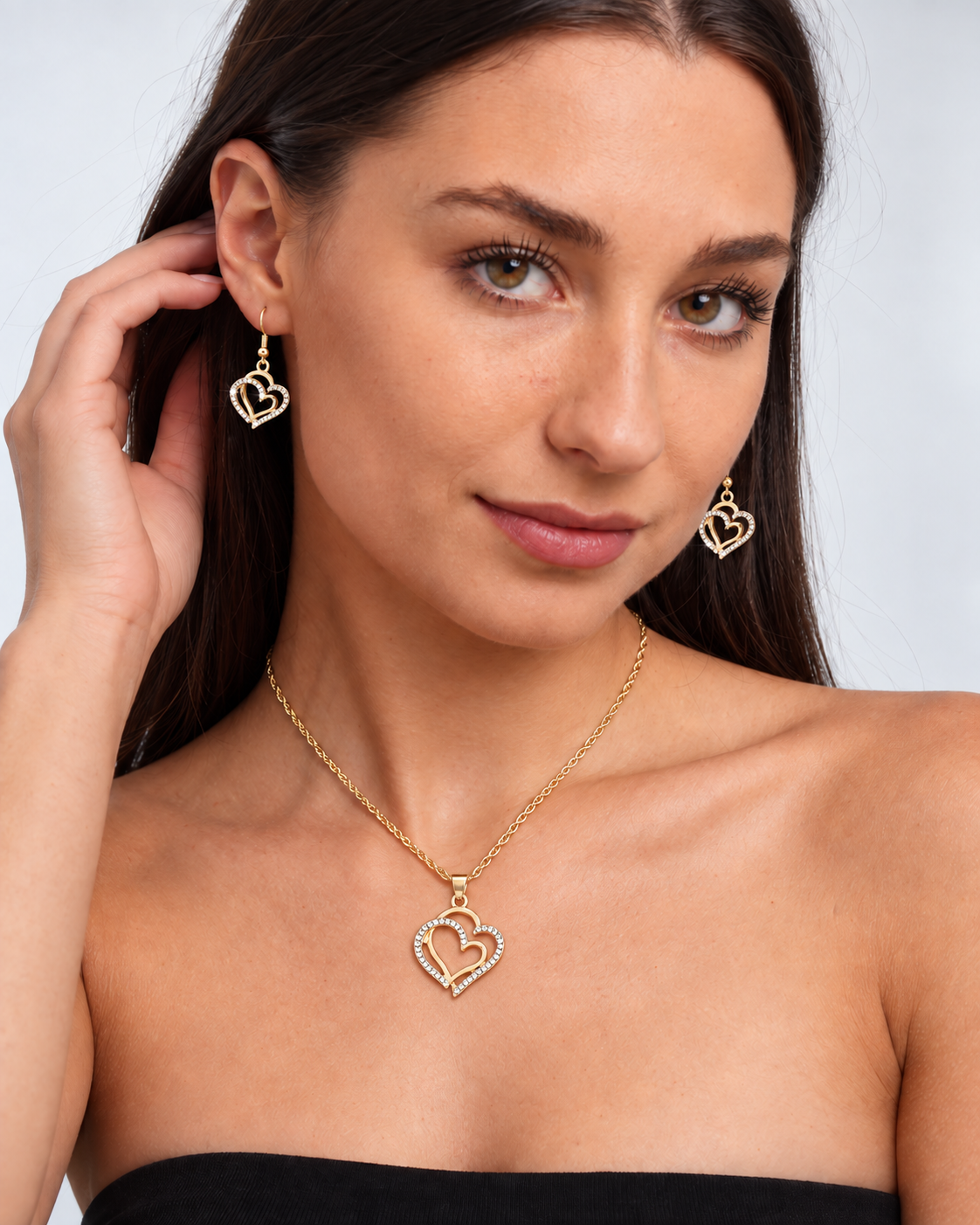 Double Heart Crystal Necklace & Earring Set in Gold, worn by a model in a three-quarter portrait - Vessaly