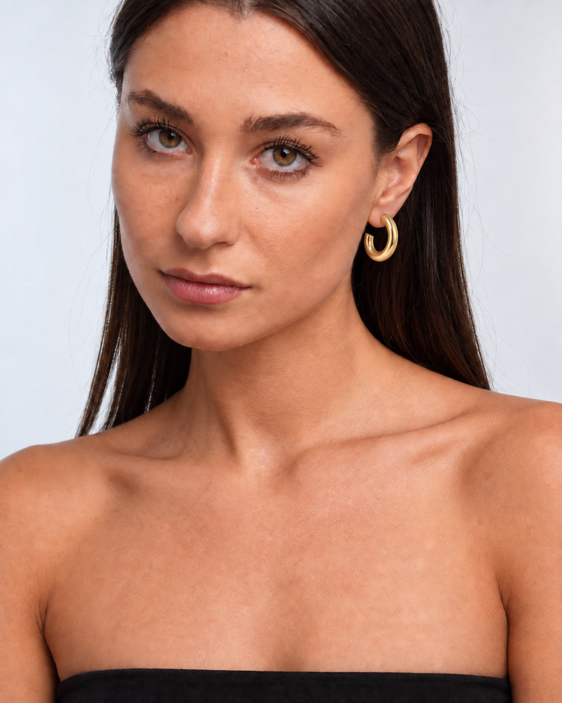 Chunky 14K gold-plated statement hoop earrings worn by a brunette model - portrait