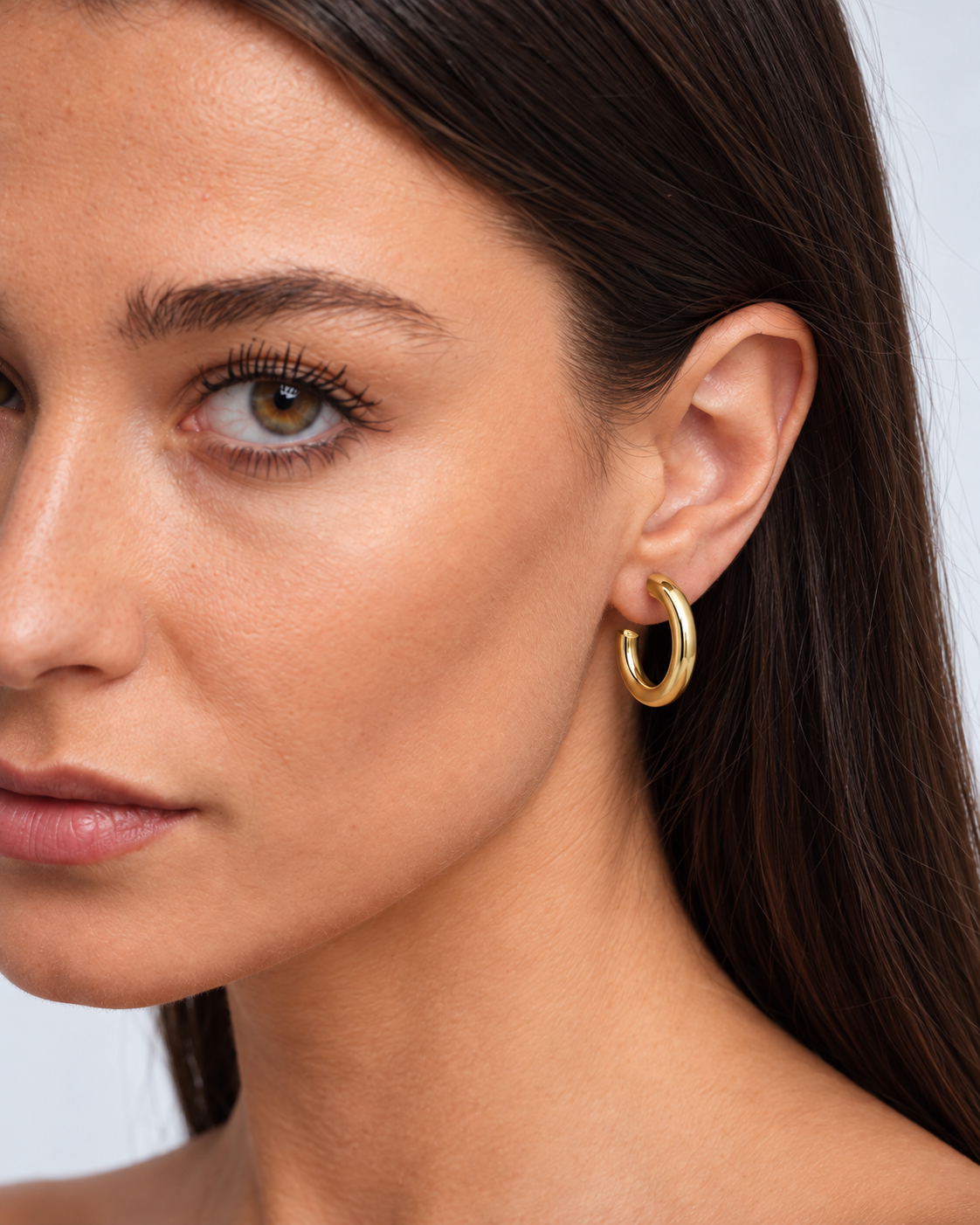 Chunky 14K gold-plated statement hoop earrings worn by a brunette model - close-up