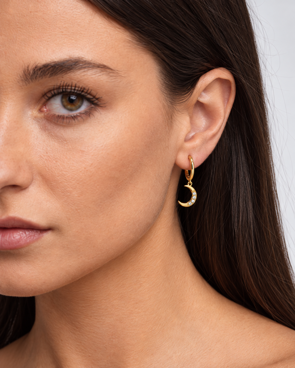 14K gold-plated star and moon dangle hoop earrings worn by a brunette model - crescent close-up